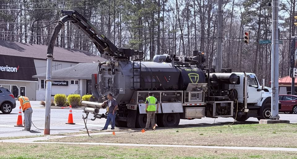 Hydro excavation vactor truck with boom arm extended performing non-destructive utility excavation on a commercial job site