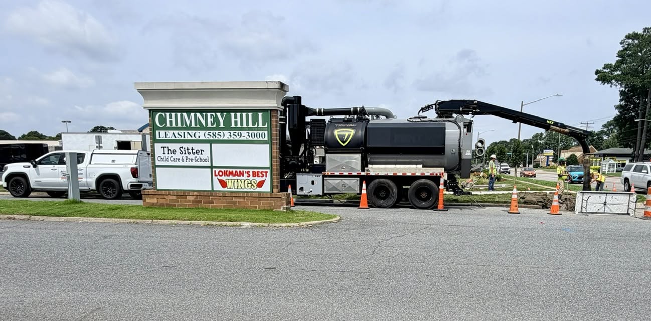 Hydro excavation vacuum truck with extended boom arm performing vacuum excavation at a commercial property