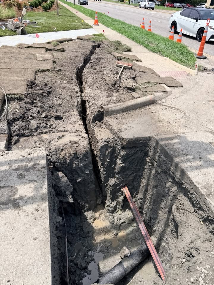 Narrow slot trench dug alongside a sidewalk using hydro excavation, exposing conduit with minimal surface disturbance